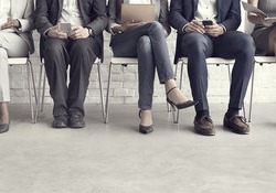 A line of candidates sitting on chairs waiting to be called in for an interview